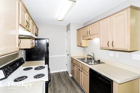 A kitchen with a black stove top oven and wooden cabinets.