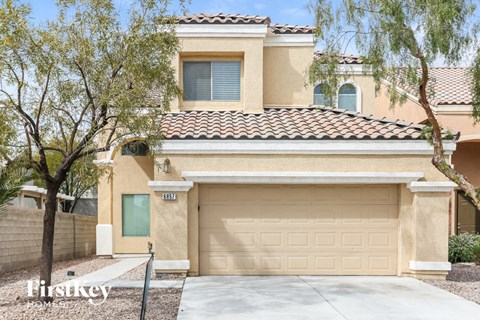 a tan house with a garage door and a tree