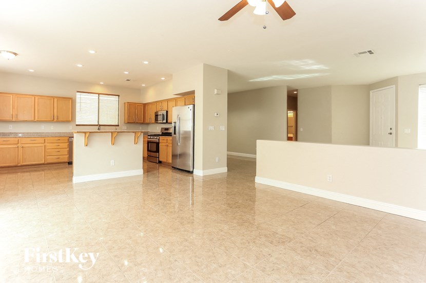 an open kitchen and living room with tile flooring and wood cabinets