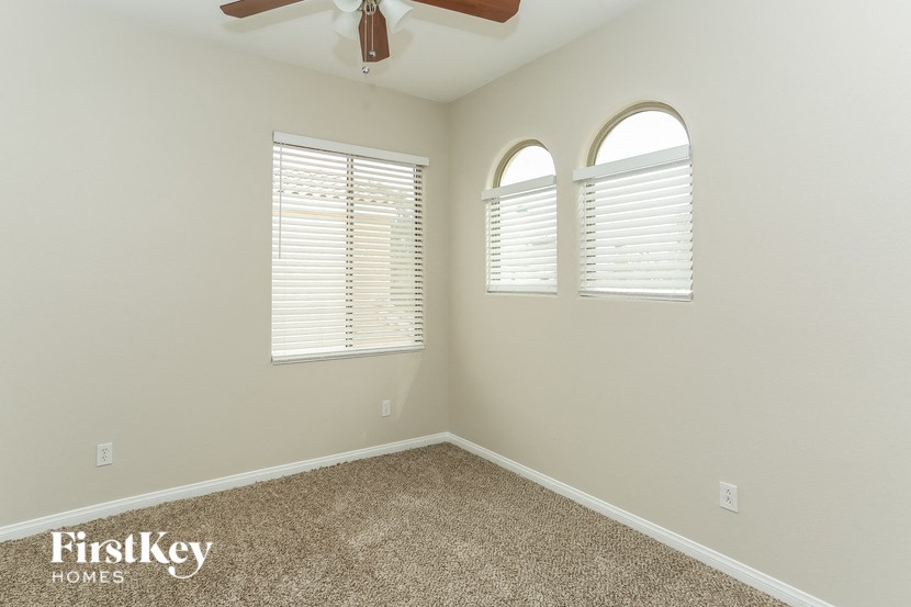 an empty room with two windows and a ceiling fan