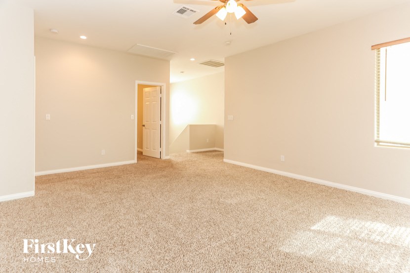 the spacious living room with carpeting and a ceiling fan