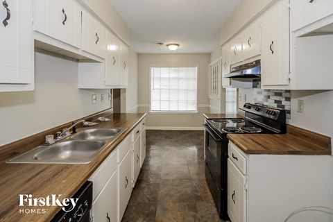 a kitchen with white cabinets and black appliances and a window