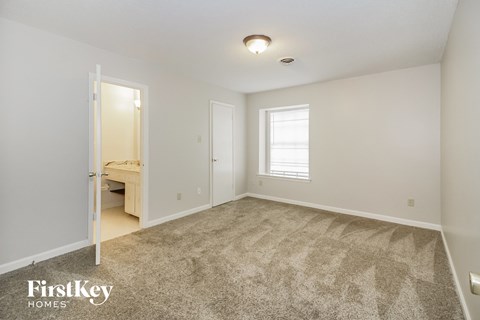 a spacious living room with carpet and a door to a bathroom