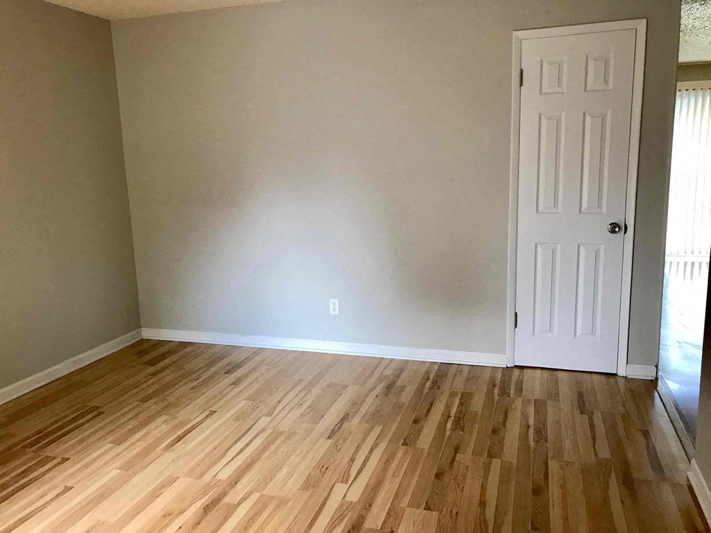 a room with wooden floors and a white wall and a door