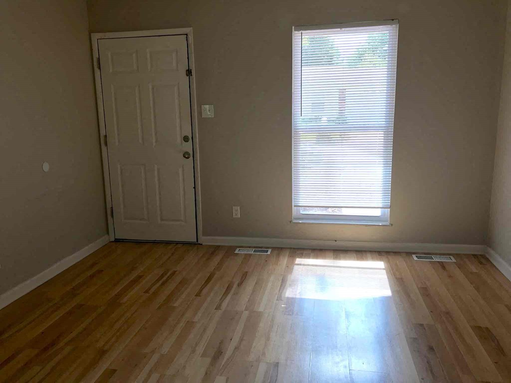 a room with wooden floors and a door and a window