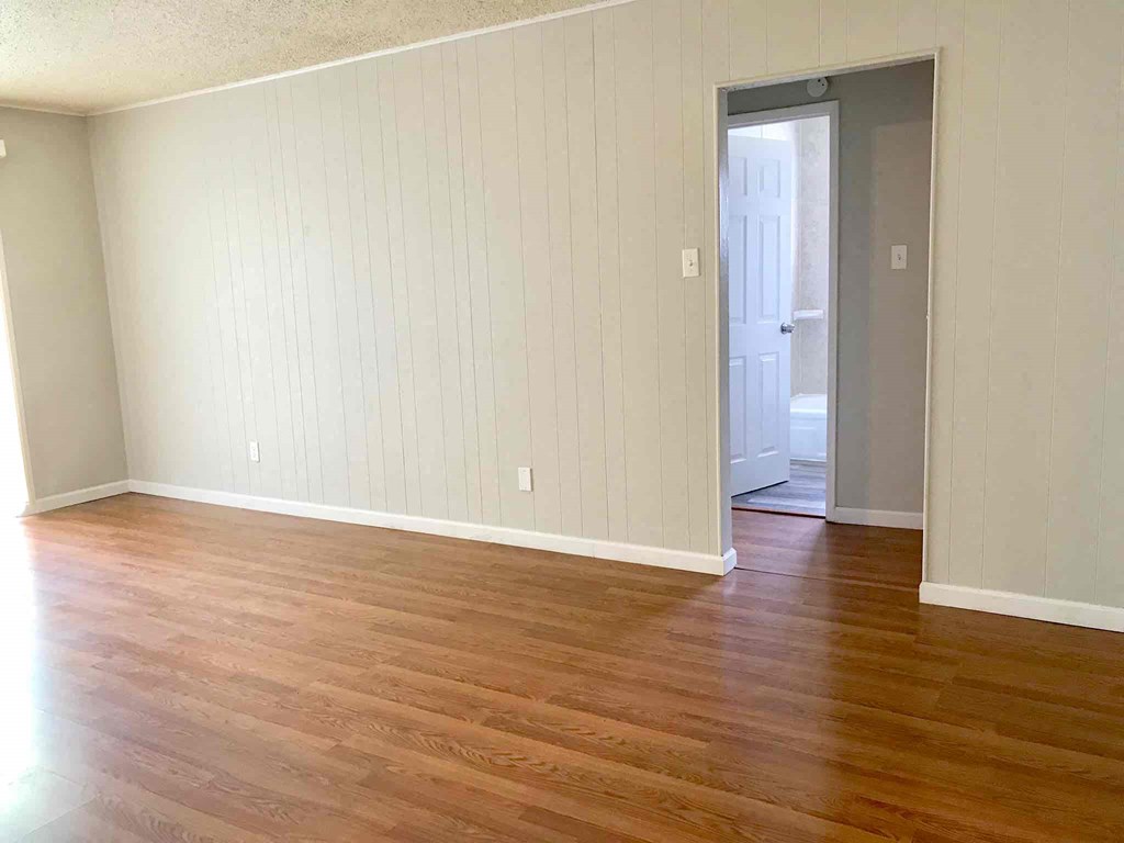 an empty living room with wood floors and a door to a closet