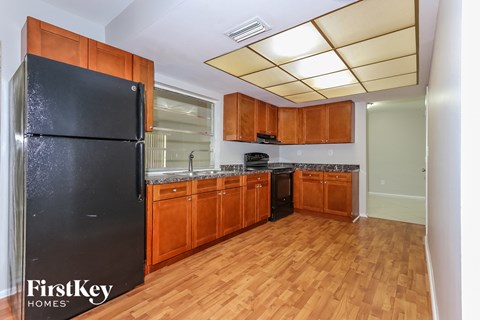 A kitchen with wooden cabinets and a black fridge.