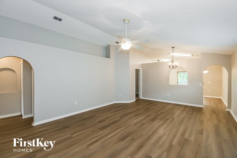 A spacious room with wooden floors and a ceiling fan.