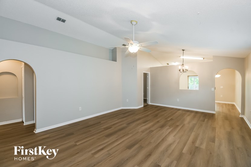 A spacious room with wooden floors and a ceiling fan.