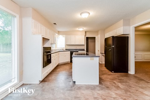 A kitchen with white cabinets and a black refrigerator.