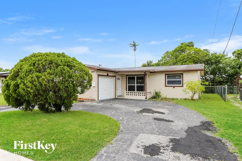 A house with a driveway and a tree in front of it.