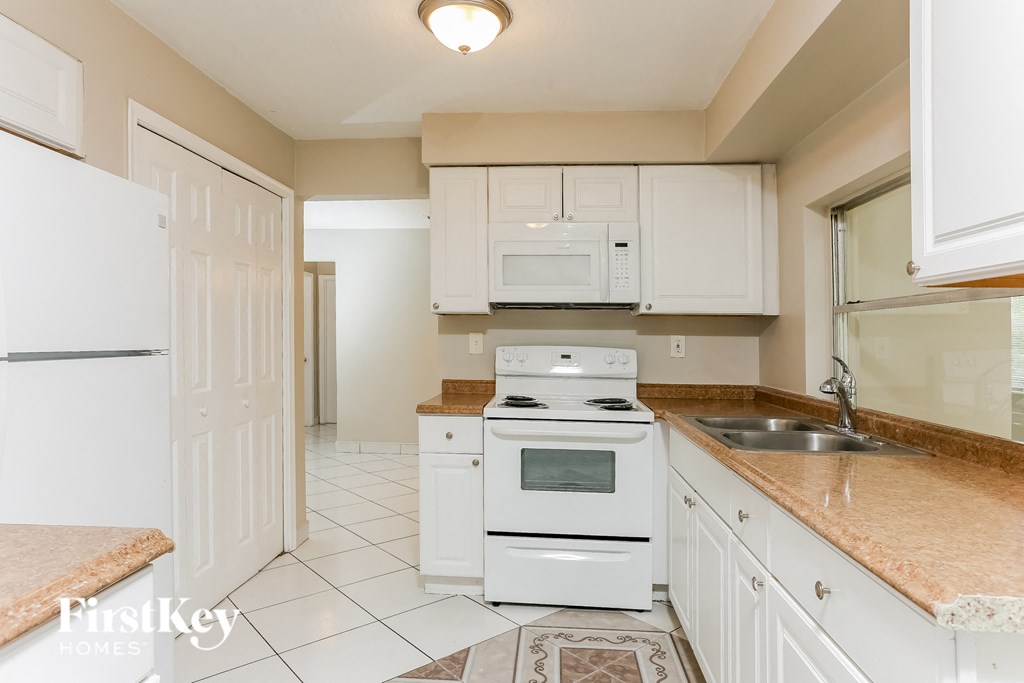 A kitchen with white appliances and cabinets.