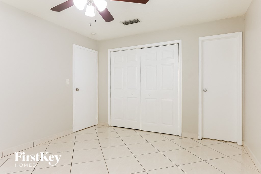 A room with a ceiling fan and three doors.
