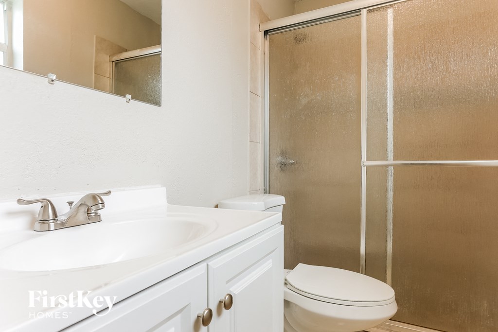 A white bathroom with a toilet, sink, and shower.
