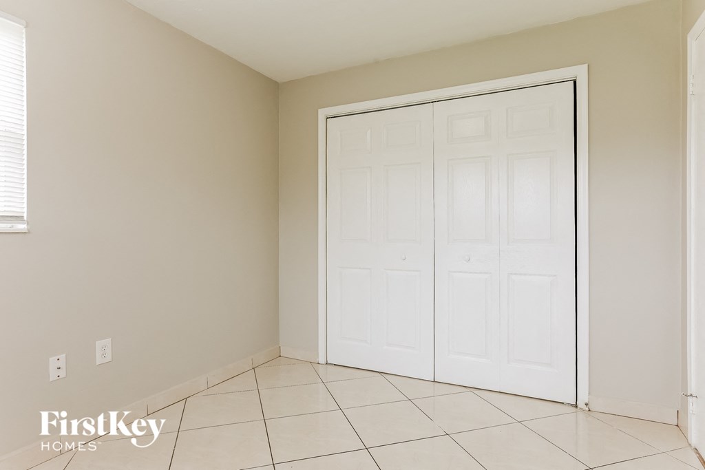A white closet door in a room with a tiled floor.