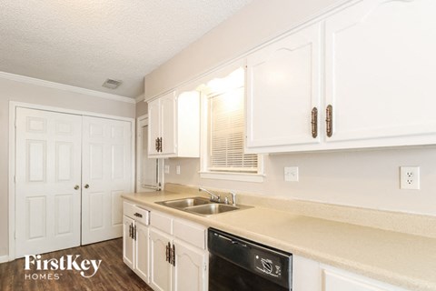 A kitchen with white cabinets and a black dishwasher.