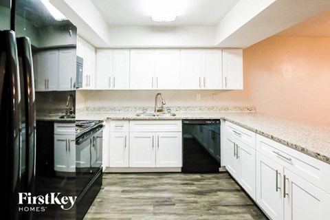 an empty kitchen with white cabinets and black appliances