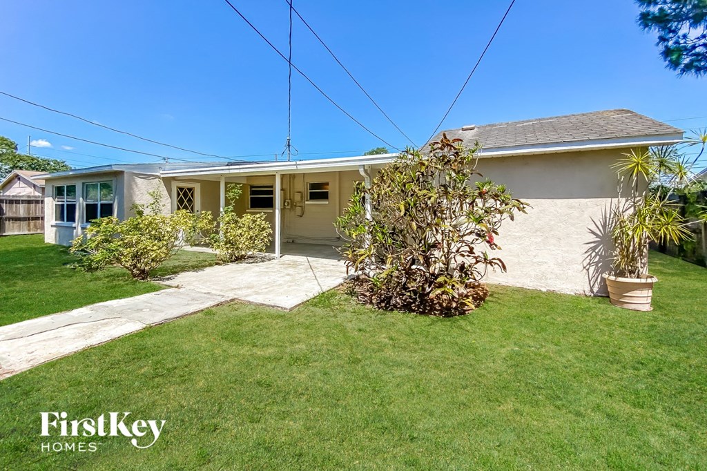 a small white house with a lawn and a driveway