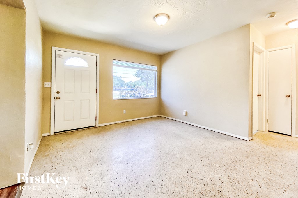 an empty living room with a white door and a window