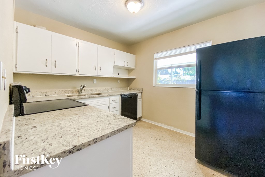 a kitchen with white cabinets and a black refrigerator