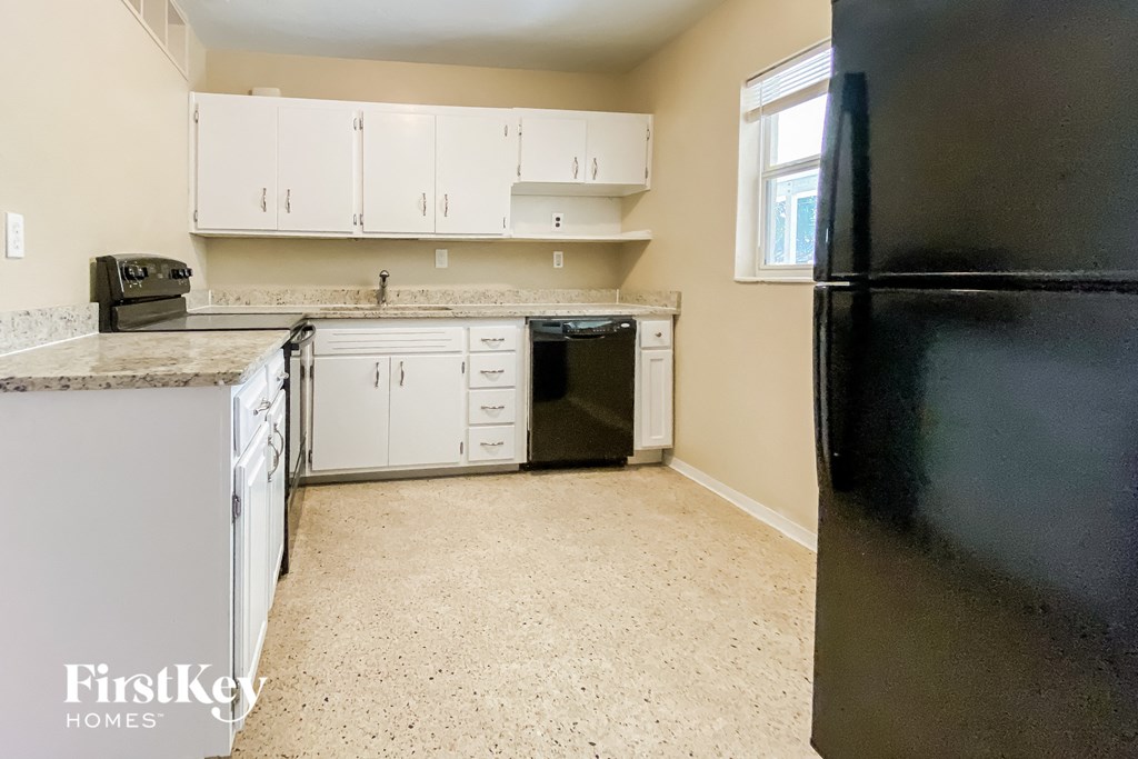 a kitchen with white cabinets and a black refrigerator
