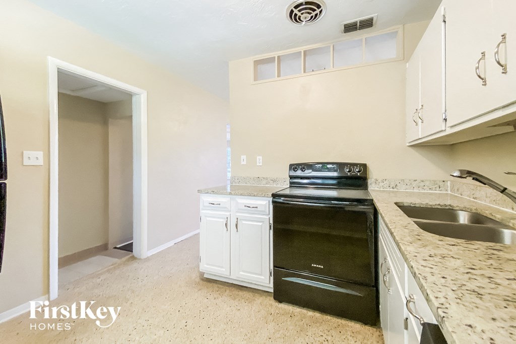a kitchen with white cabinets and a black stove and a sink