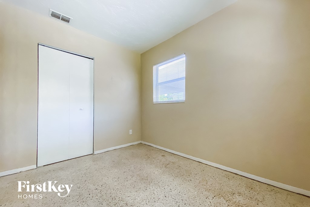 a bedroom with white walls and a window and a door to a closet