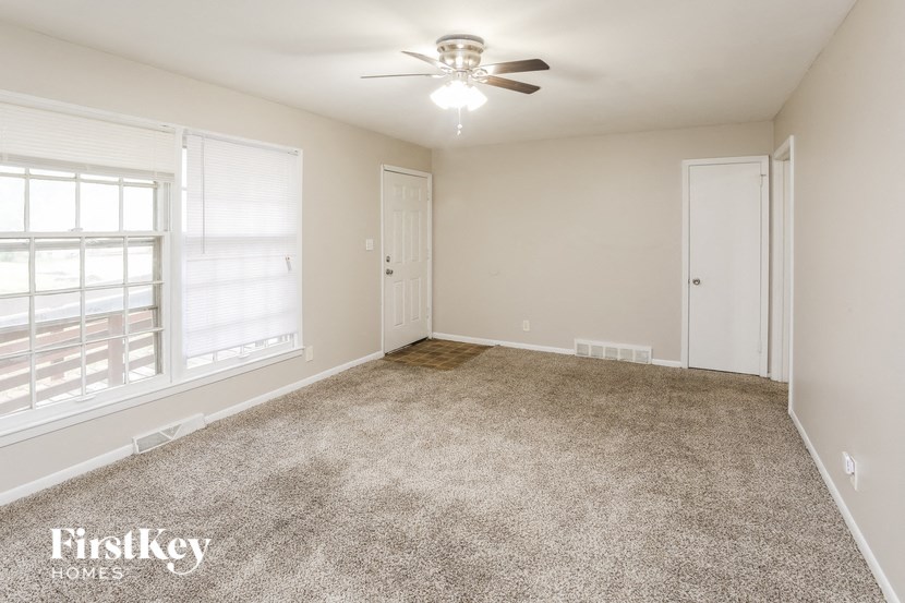 A spacious room with a carpeted floor and a ceiling fan.