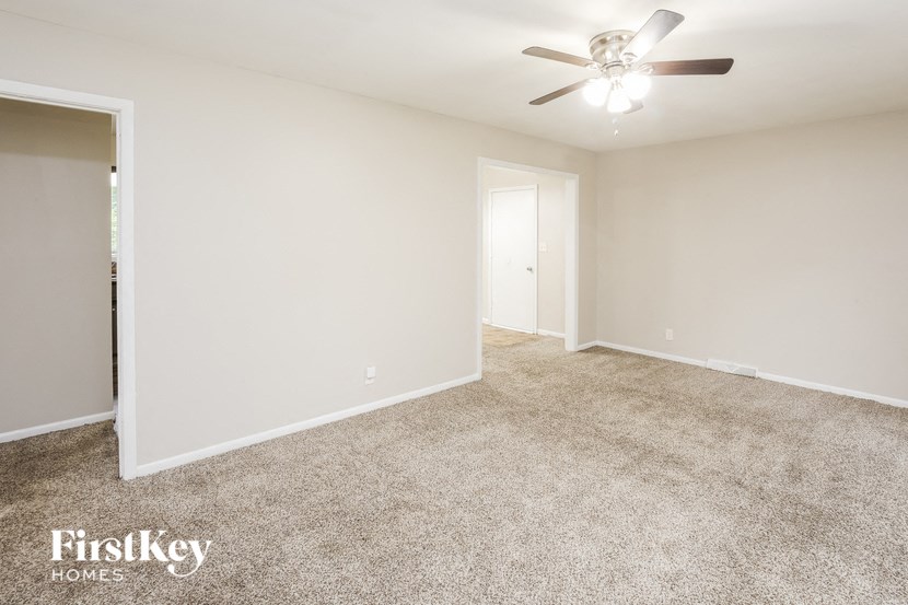 A spacious room with a ceiling fan and carpeted floor.