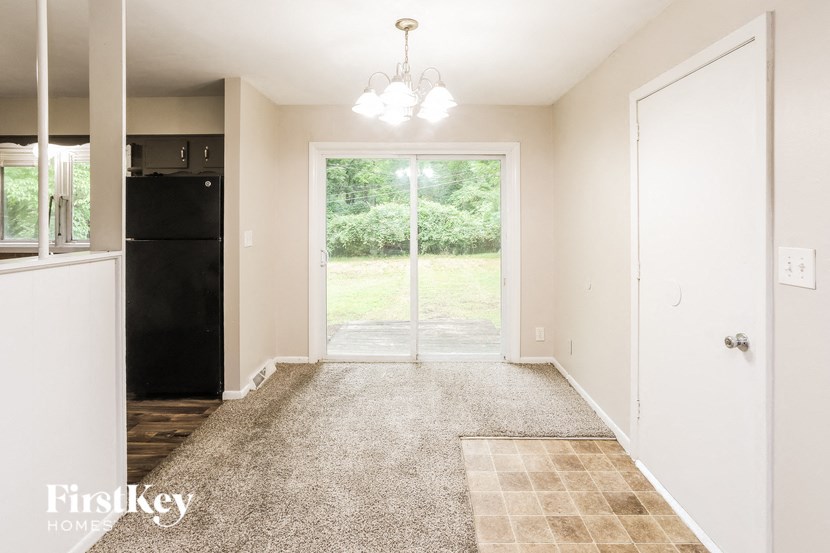 A room with a carpeted floor and a door leading to a backyard.