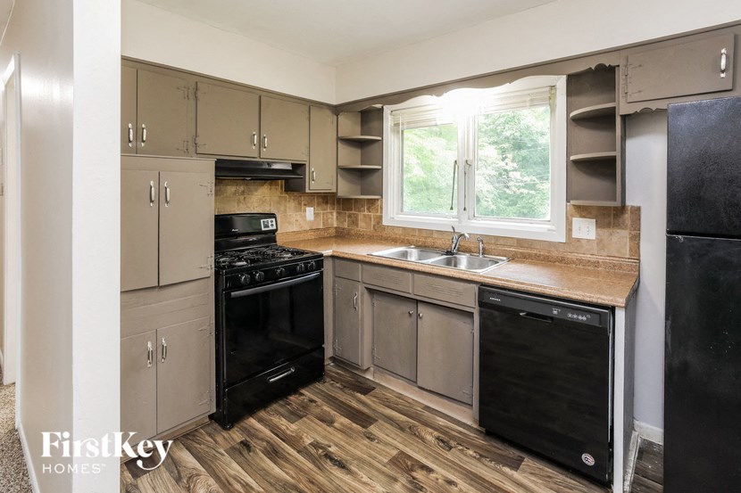 A kitchen with wooden floors and black appliances.