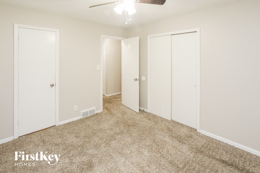 A spacious room with a carpeted floor and a ceiling fan.