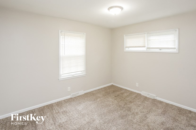 A room with a carpeted floor and two windows.