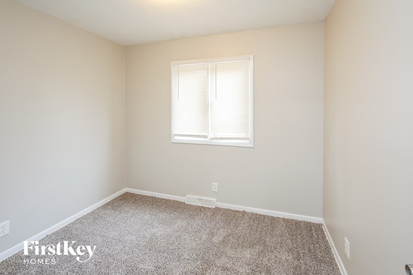 A room with a carpeted floor and a window with blinds.