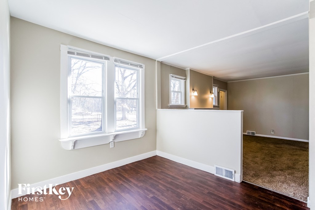 the living room and dining room of a home with wood floors and a window