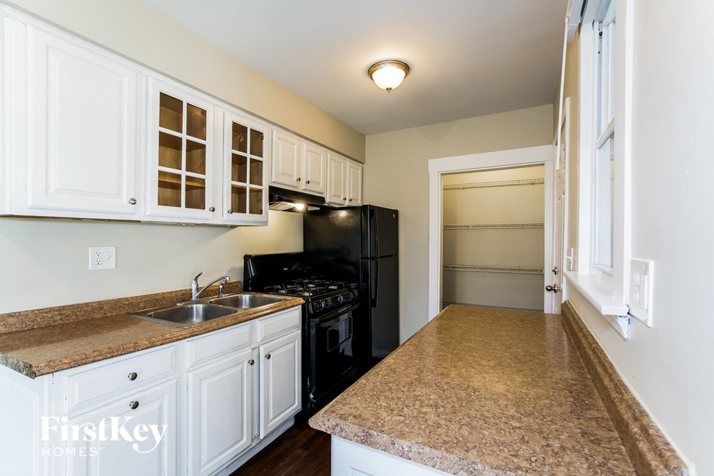 a kitchen with white cabinets and a granite counter top and a black refrigerator