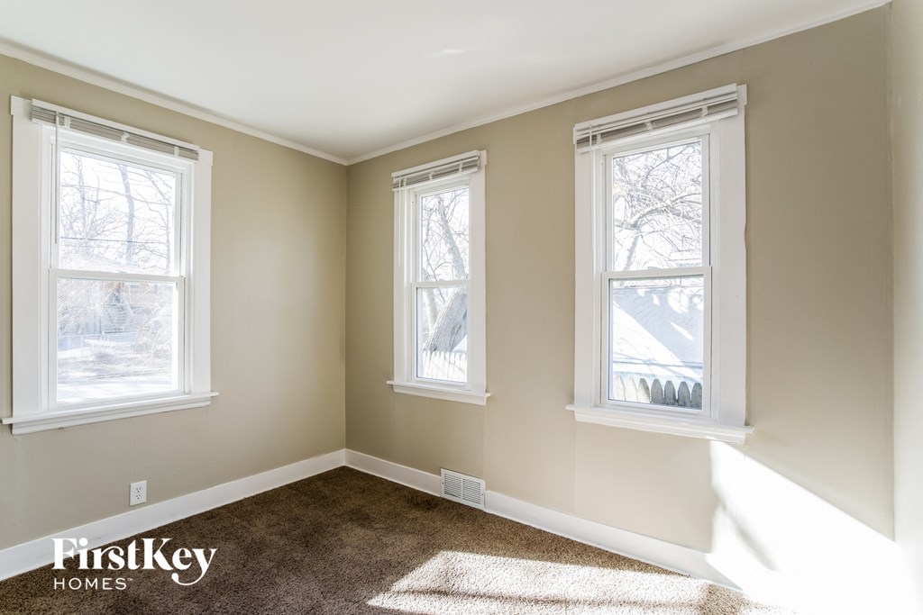 a bedroom with three windows and a carpeted floor