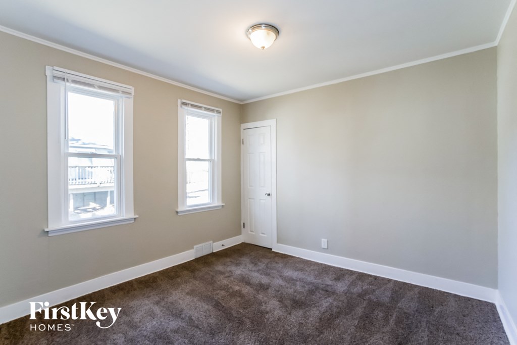 a living room with carpet and two windows and a door