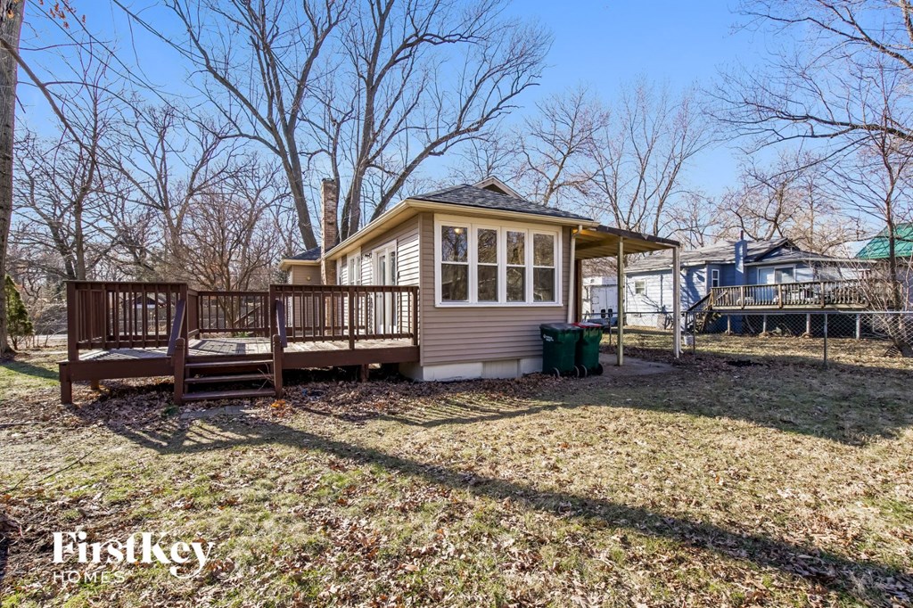 a small tan house with a porch and a deck
