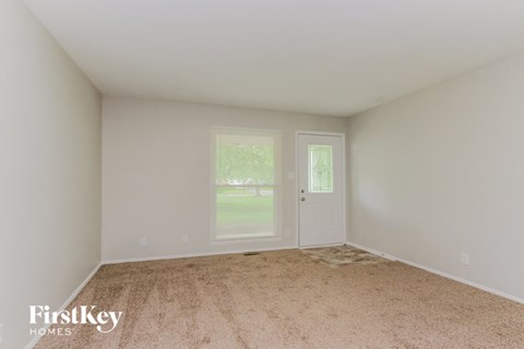 A room with a carpeted floor and two doors, one of which is open.