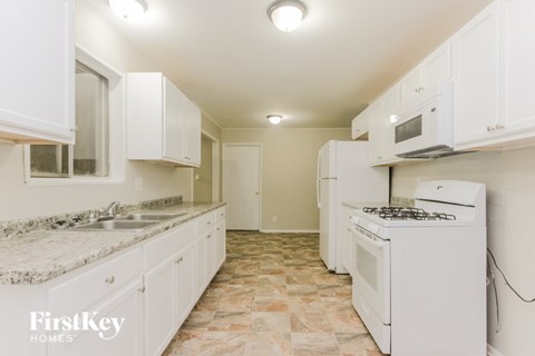A kitchen with white appliances and cabinets.