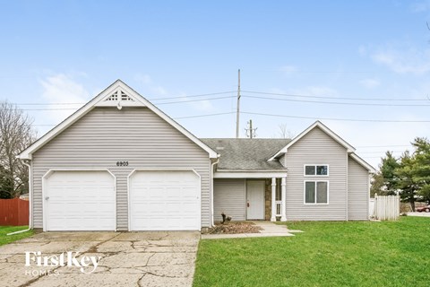 a white house with two garage doors and a lawn