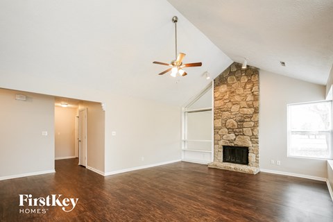 a living room with a stone fireplace and a ceiling fan