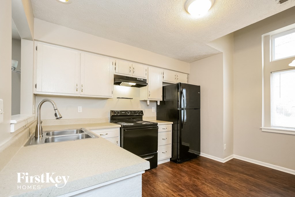 an empty kitchen with white cabinets and black appliances