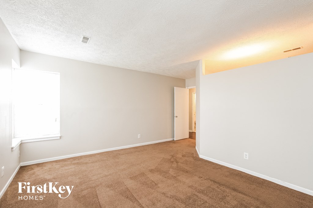 the living room and dining room of an apartment with carpeting and white walls