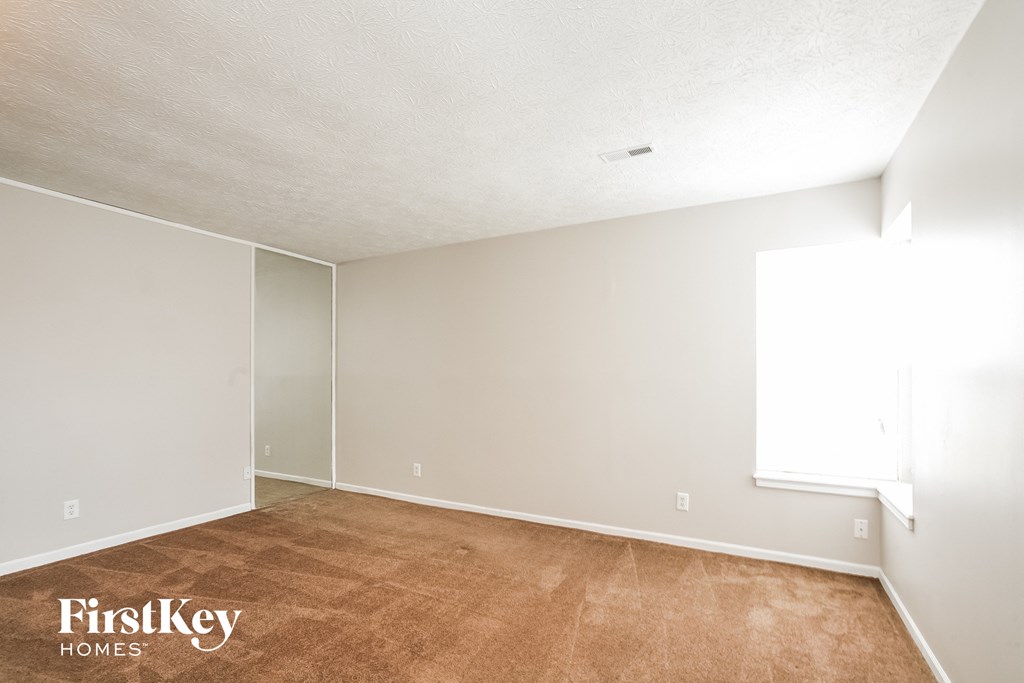 the living room of an apartment with a wood floor and white walls