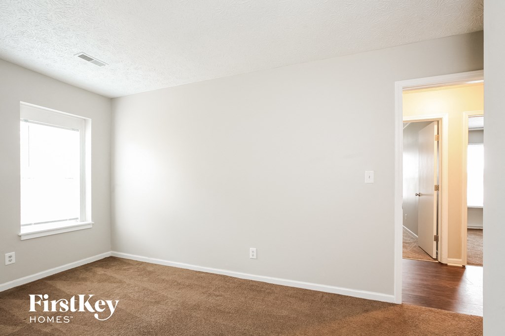 the spacious living room with white walls and wood flooring