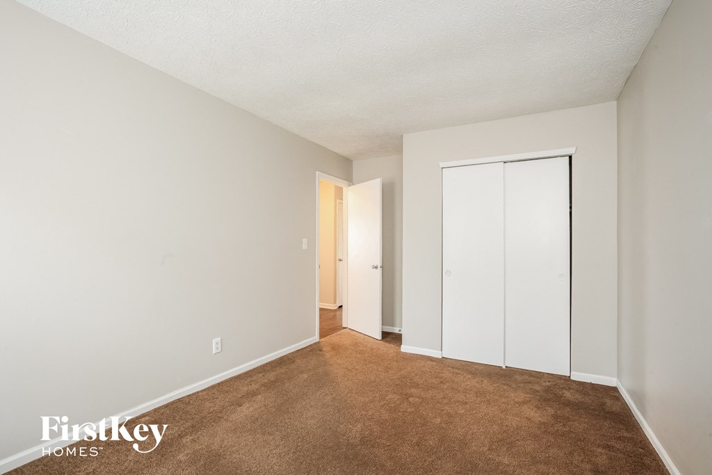 a bedroom with a carpeted floor and a closet