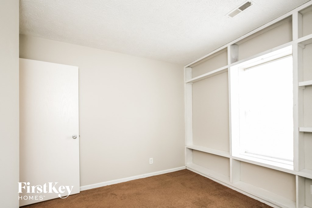 a bedroom with white walls and white shelves and a white closet