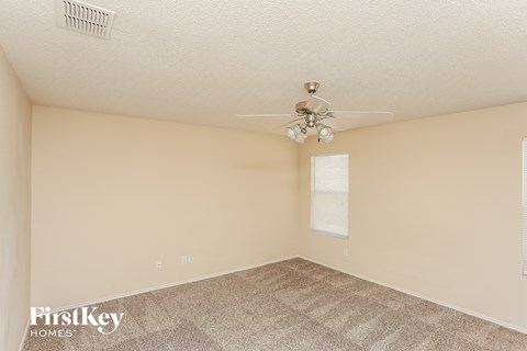 a spacious living room with carpet and a ceiling fan